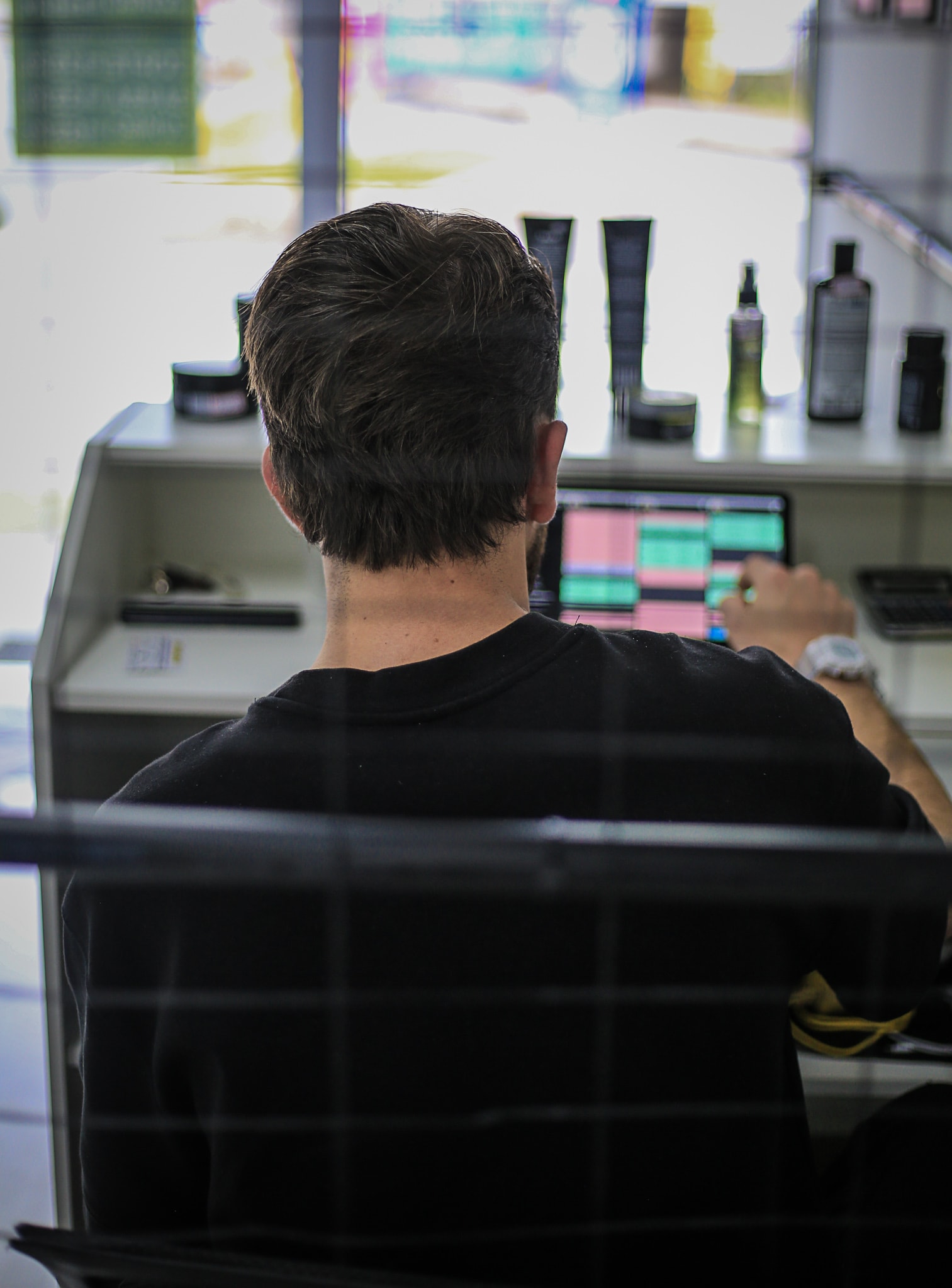 Cliente visto de costas na cadeira da MC Barbearia, em frente à bancada